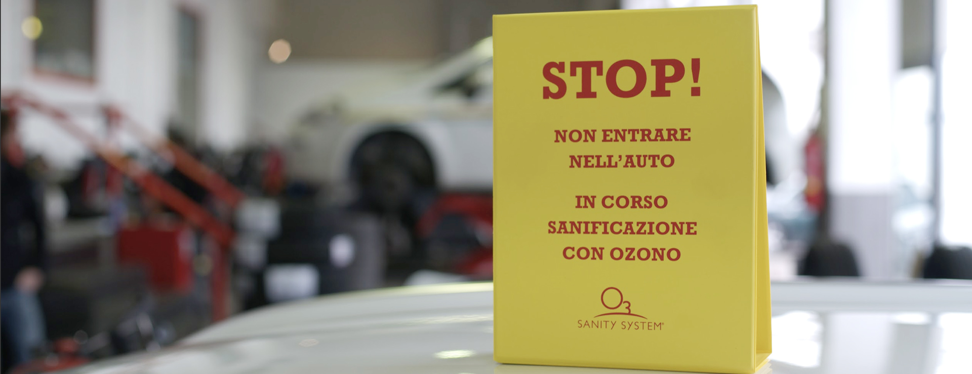 cartello 'sanificazione in corso' appoggiato sul tetto dell'auto